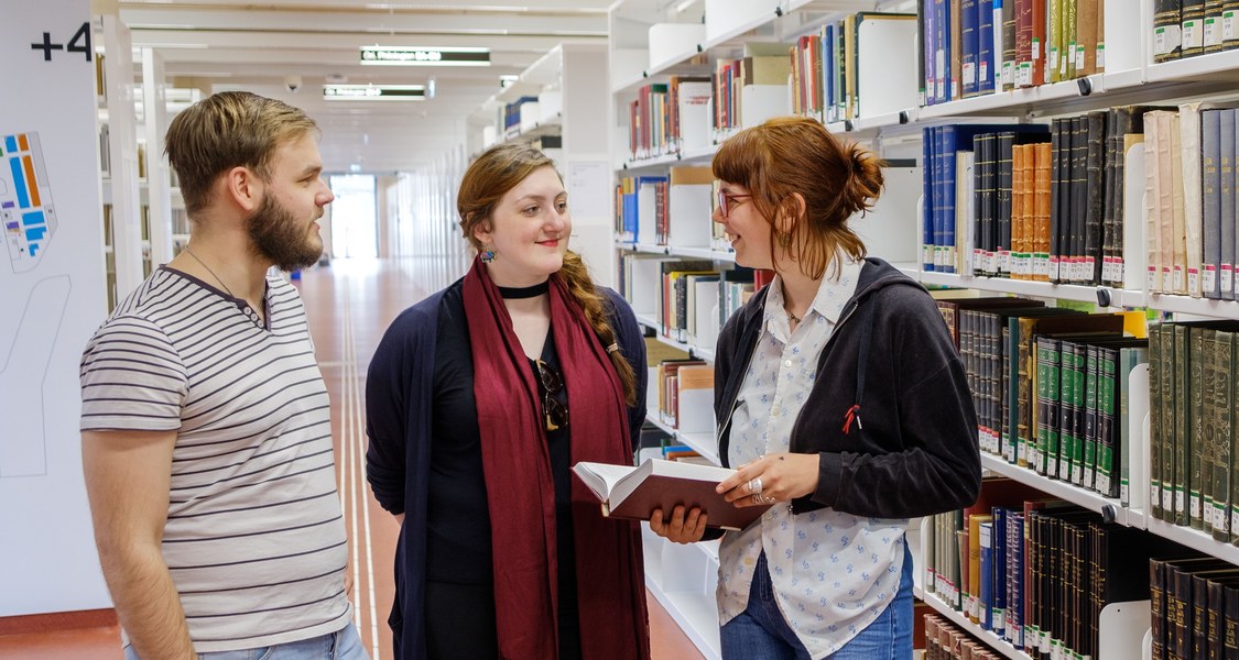 Studierende unterhalten sich in der Universitätsbibliothek