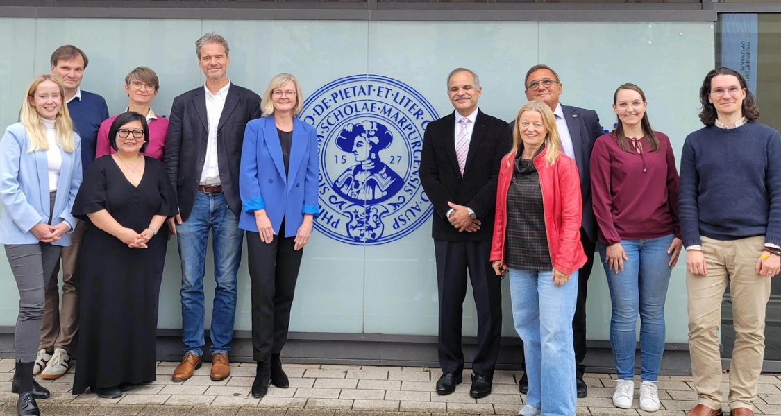 Menschen vor dem Hauptgebäude der Uni Marburg mit Philipp-Logo