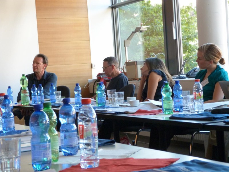 Blick in den Konferenzraum auf Tagungsteilnehmer und Tagungsteilnehmerinnen