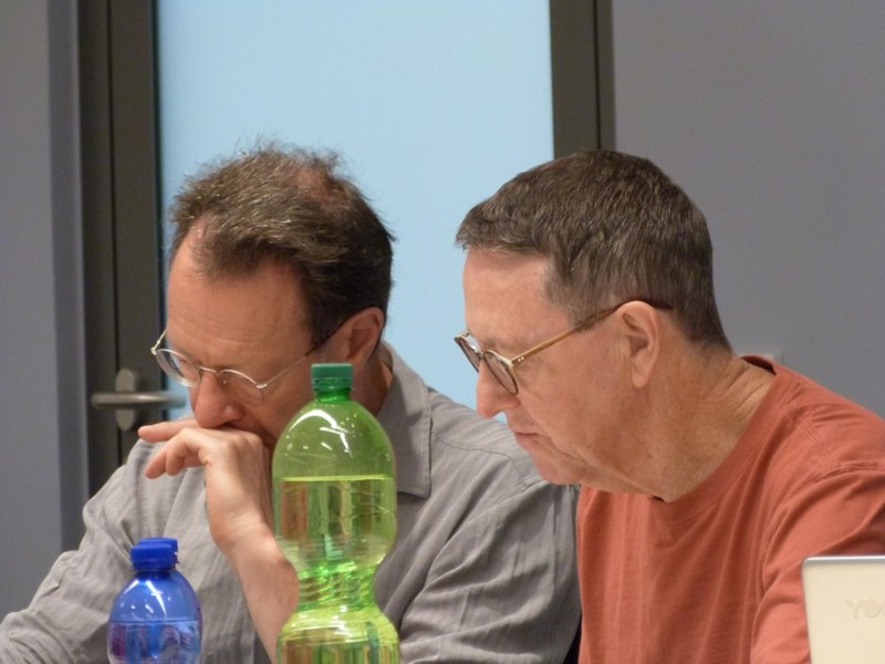 zwei Tagungsteilnehmer richten den Blick nach unten auf den Tisch