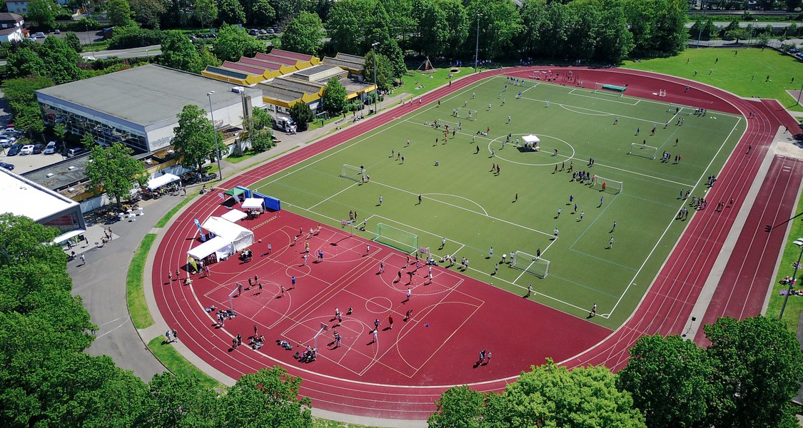 Das Foto zeigt eine Luftaufnahme vom Unistadion in Marburg mit sich bewegenden Menschen und einige Zelte