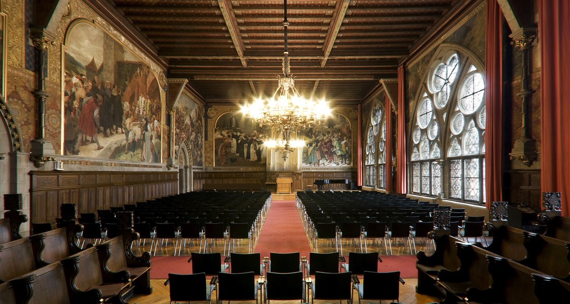 Blick in die durch einen Kronleuchter erleuchtete Aula der Alten Universität