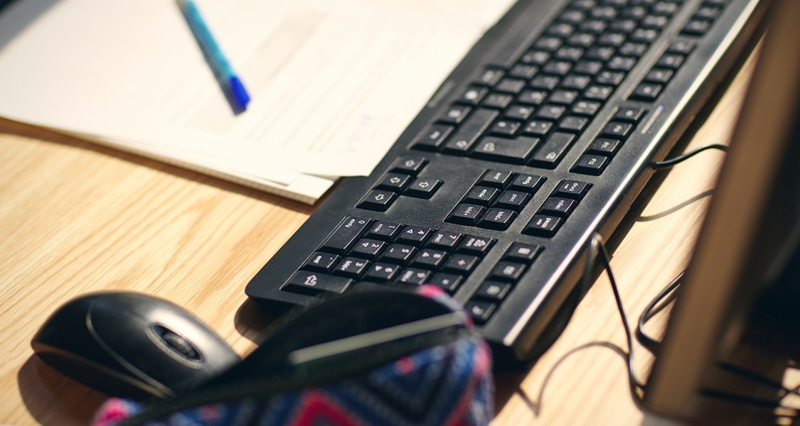 Close-up view of a desk with a keybord, a pen, and paper