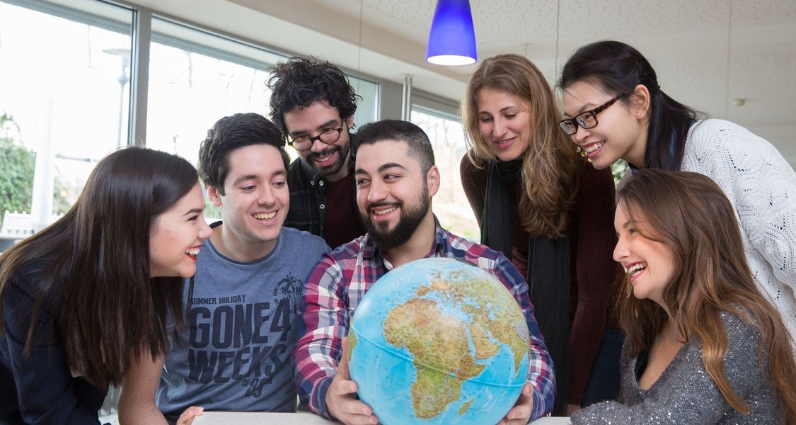Several students gathered around a globe.